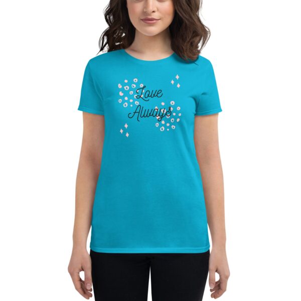 A woman is wearing a bright turquoise t-shirt with the text "Love Always" printed in black  surrounded by decorative elements  while standing against a plain white background.
