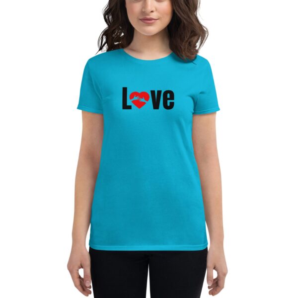 A woman is wearing a bright turquoise t-shirt featuring the word "Love" in black with a red heart symbol. She is in a neutral setting  facing forward with a soft expression.