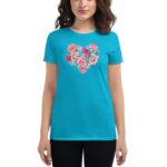 A woman is wearing a bright turquoise t-shirt featuring a floral heart graphic. She stands facing forward with her hands by her sides against a plain background.