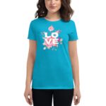 A woman is wearing a vibrant turquoise t-shirt featuring the word "LOVE" in bold white letters surrounded by floral designs  standing against a neutral background.