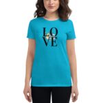 A woman wearing a bright teal t-shirt displays a graphic that reads LOVE with floral elements integrated into the design against a plain background  conveying a cheerful  positive vibe.