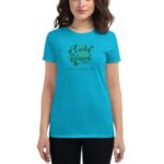 A woman wears a bright turquoise t-shirt featuring green text that reads not lucky just blessed with a clover design and the phrase happy St Patrick's Day underneath.
