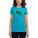 A woman stands wearing a bright blue shirt featuring a green heart and a shamrock with the text Happy St. Patrick's Day  celebrating the festive occasion in a casual setting.