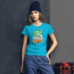 A young woman wears a bright blue t-shirt featuring a graphic of a vintage van surrounded by palm trees and the text hello sunshine  posed against a textured dark wall.