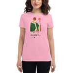 A person stands wearing a pink t-shirt featuring a cartoonish figure holding a staff  surrounded by small clovers  with the word LUCKY prominently displayed below the figure.