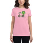 A woman is wearing a pink t-shirt featuring the text "LIVE THE DREAM HAPPY ST. PATRICK" alongside a green flower design  highlighting a festive theme related to St. Patrick's Day.