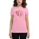 A person wearing a pink t-shirt stands holding their hands at their sides. The t-shirt features a red heart design with chocolates and a flower motif  creating a festive appearance.