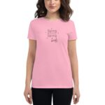 A woman wearing a light pink t-shirt stands smiling. The shirt features the text "love love birds" in a playful font. She is in a neutral environment.