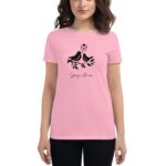 A woman wears a pink t-shirt featuring a black graphic of two birds on a branch with leaves and the text Spring in the air displayed below in a cursive font.