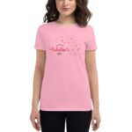 A woman in a pink t-shirt displays a cheerful graphic with text and hearts saying Happy Valentine's Day against a simple background. She appears friendly and festive.