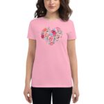 A woman is wearing a pink t-shirt featuring a floral heart design composed of various colorful flowers  set against a neutral background  portraying a casual and vibrant style.