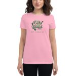 A woman is wearing a pink t-shirt featuring the text "Not Lucky Just Blessed" with green accents and shamrocks  celebrating St. Patrick's Day in a casual setting.