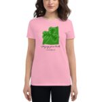 A woman stands wearing a pink t-shirt featuring a green four-leaf clover graphic and text that reads Enjoying your luck It's Saint Patrick's Day in a casual setting.