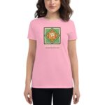 A woman stands wearing a pink t-shirt featuring a green diamond-shaped graphic with a white shamrock and the text HAPPY ST PATRICK'S DAY in a festive context.