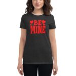 A woman is wearing a dark gray t-shirt featuring the text "BE MINE" in large red letters surrounded by small red hearts  suggesting a romantic theme.