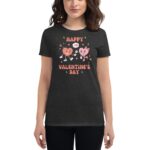 A woman wears a dark t-shirt featuring cartoon hearts celebrating Valentine's Day with cheerful expressions surrounded by flowers and stars  conveying a festive and playful theme.