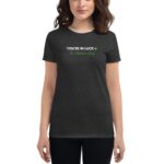 A woman wears a dark gray t-shirt featuring the text YOU'RE IN LUCK with a shamrock and the phrase St. Patrick's Day in green. She appears to be smiling.