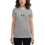 A woman is wearing a gray t-shirt featuring a smiling face graphic with the text "HAVE A LUCKY DAY" above it in a playful style surrounded by small clovers