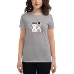 A woman wearing a gray t-shirt holds the shirt up featuring two cartoon cats with hearts above them along with the text Happy Valentine's Day.