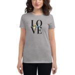 A woman stands wearing a gray t-shirt featuring the word "LOVE" in bold black letters with floral elements behind. She is positioned against a neutral background.