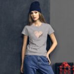 A woman stands confidently wearing a gray t-shirt with a heart design and the text Happy Valentine's Day paired with loose jeans and a dark beanie in a minimalist  dark setting.