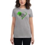 Gray t-shirt features a design with green accents including a heart and a shamrock along with the text Happy St. Patrick's Day worn by a woman in a casual setting
