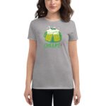 A woman wears a gray t-shirt featuring a graphic of two beer mugs with foam and the text CHEERS!! HAPPY ST PATRICK'S DAY set against a casual indoor setting.