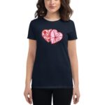 A woman wears a navy t-shirt featuring a heart design split into two sections one colored red with candy illustrations and the other pink with a decorative pattern against a simple background.