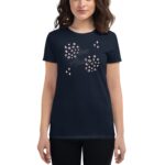 A woman wearing a navy t-shirt featuring a design with the text Love Always surrounded by circular shapes and small sparkles stands against a plain background.