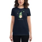 A woman wears a dark navy t-shirt featuring a cartoon gnome in a green hat with shamrocks above it accompanied by the text St. Patrick's Day on the front.
