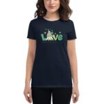 A woman wears a navy t-shirt displaying the word "Love" in bright green with a gnome wearing a striped hat among shamrocks and the text "Happy St. Patrick's Day" underneath.