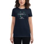 A person wears a dark navy t-shirt featuring a graphic design with green shamrocks and the text "LUCKY HAPPY ST. PATRICK'S DAY" celebrating the holiday.