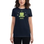A woman wears a dark t-shirt featuring a large green leprechaun hat design surrounded by four-leaf clovers with the text CHEERS HAPPY ST. PATRICK'S DAY visible in the center.