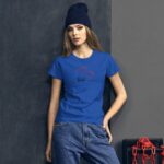 A young woman is standing against a dark wall wearing a bright blue t-shirt with a heart design and the word love while sporting a dark beanie and relaxed denim pants.
