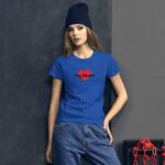 A young woman is wearing a blue t-shirt featuring a red heart graphic with the text My Heart. She stands against a textured dark wall with a red chain nearby.
