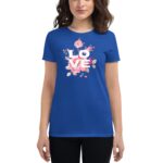 A woman wears a blue t-shirt featuring a floral design with the word LOVE prominently displayed in white letters  set against a neutral background.