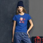 A young woman wearing a bright blue t-shirt with a hedgehog graphic stands against a dark wall while casually leaning. She has long hair and is wearing a dark beanie.