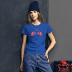 A woman wearing a blue t-shirt with red illustrations of cherubs and the word love stands against a textured gray wall with a chain in the background.