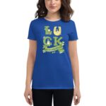 A blue t-shirt features a graphic design spelling "LUCK" with a horseshoe and shamrocks alongside the text "ST. PATRICK'S DAY " worn by a woman with brown hair.
