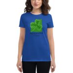 A woman stands wearing a blue t-shirt featuring a green shamrock design and text that reads Enjoying your luck It's Saint Patrick's Day against a plain background.