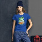 A young woman wearing a blue t-shirt with a colorful graphic stands against a dark wall. She has long hair and a beanie  exuding a casual style and vibe.