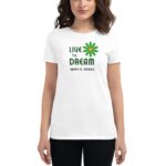 A woman is wearing a white t-shirt featuring a green flower graphic and the text "LIVE The DREAM HAPPY ST. PATRICK" in a festive context suitable for St. Patrick's Day.