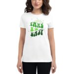 A woman stands wearing a white t-shirt featuring green text that reads TAKE IT EASY surrounded by playful graphics in a casual  relaxed setting.