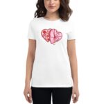 A woman wearing a white t-shirt stands with her hand at her side. The shirt features a graphic of two intertwined hearts decorated with various sweets and patterns.