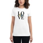 A woman wearing a white t-shirt with the word "LOVE" printed in black letters and surrounded by floral designs stands against a plain background.