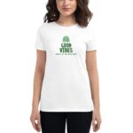 A woman wearing a white t-shirt stands facing the camera. The shirt features the text "GOOD VIBES" and "HAPPY ST.PATRICK'S DAY" in green  evoking a festive atmosphere.