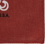 A red fabric with white circular design and black text indicating U.S.A is displayed on the surface emphasizing a textile object's branding or label in a close-up view.