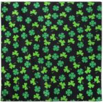 A black fabric square features numerous green shamrock patterns scattered evenly across the surface creating a vibrant and festive design that evokes themes of luck and celebration.