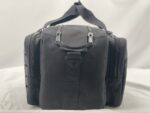 A black rectangular bag is positioned upright with zippers and a detachable strap visible the background is a neutral light color suggesting a simple display setting.