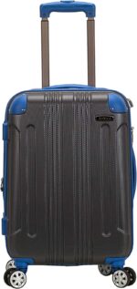 A compact suitcase with a textured gray body and blue accents stands upright featuring a telescopic handle and four wheels indicating it's ready for travel in an urban setting.